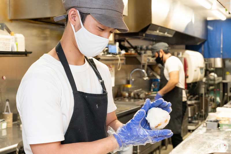 Photo of staff making onigiri in front of customers at the counter