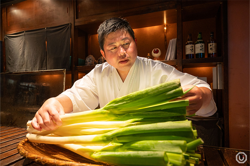 A chef selecting spring onions for cooking