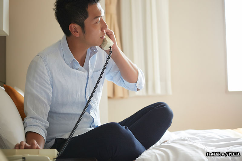 Photo of an Asian man calling the front desk from his hotel room