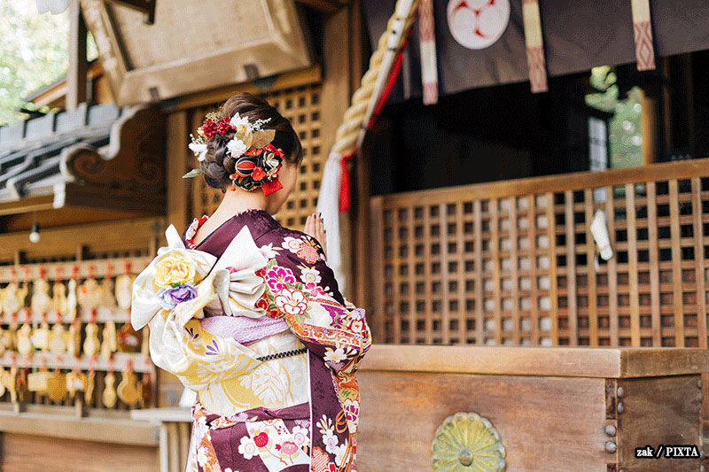 Japanese woman in a kimono praying at a Shinto shrine