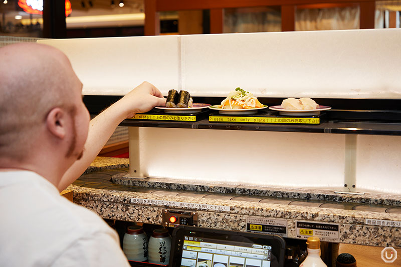 a diner choosing sushi from the track at Kodawari Kaiten-sushi Magurobito Yodobashi Akiba