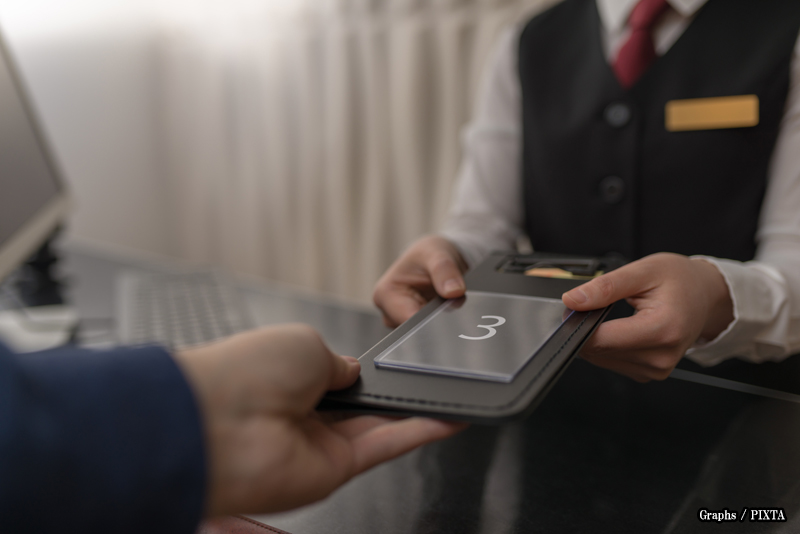 hotel receptionist giving a key to a guest