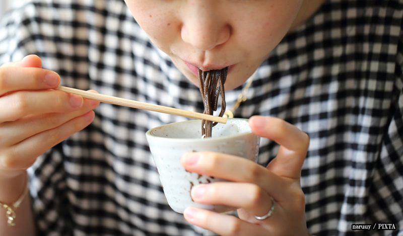 a woman slurping soba noodles