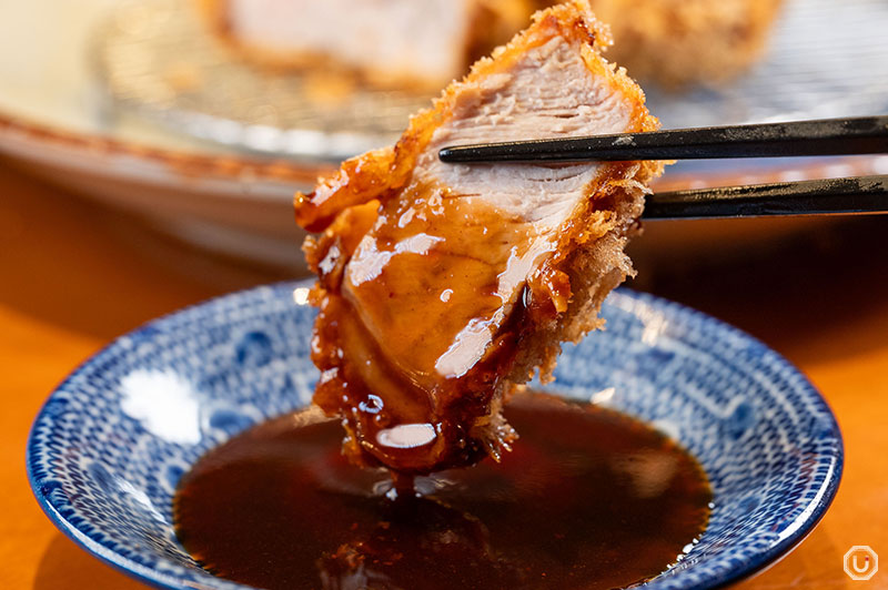 Applying sauce to a premium loin cutlet at Butagumi Shokudō