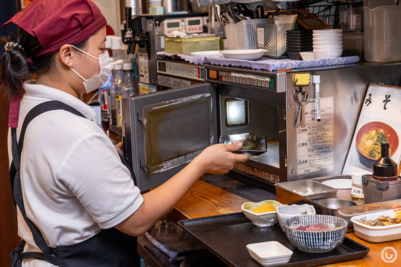 Staff warming up side dishes at Okachimachi Komachi Shokudo in Ueno